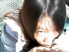 Asian woman deepthroating guys in the park in wide day light