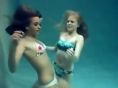 Two gals breath holding and posing underwater