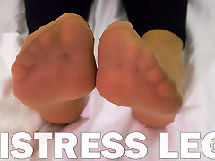 Mistress soles in fragile nylon socks is resting on the bed