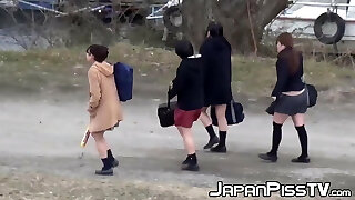 Four Japanese schoolgirls fool around outside before peeing