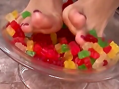 A Kinky Brunette Sticks Her Feet In Gummy Bears And Performs A Footjob Until Cumshot