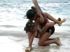 多米尼加女孩性感的摔跤在沙滩上的身体到身体