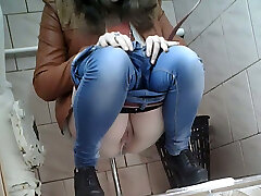 苗条的女孩在非常紧的蓝色牛仔裤拍摄在厕所的房间