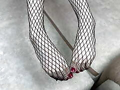Mistress in black fishnet stockings caresses her legs with pedicure