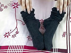 Girl in gray long socks on her legs caresses herself in bed