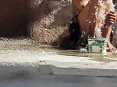 Indian sister-in-law is bathing in the open courtyard of the house, putting a finger in her burrow and rubbing the body, sister-in-law is washing the bathroom.