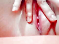 in close-up masturbating her young pussy with her fingers until it is wet