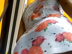An inquiring camera looks under a white dress with rose print