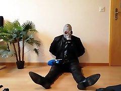 guy in leathergear and gasmask smells his sportshoes